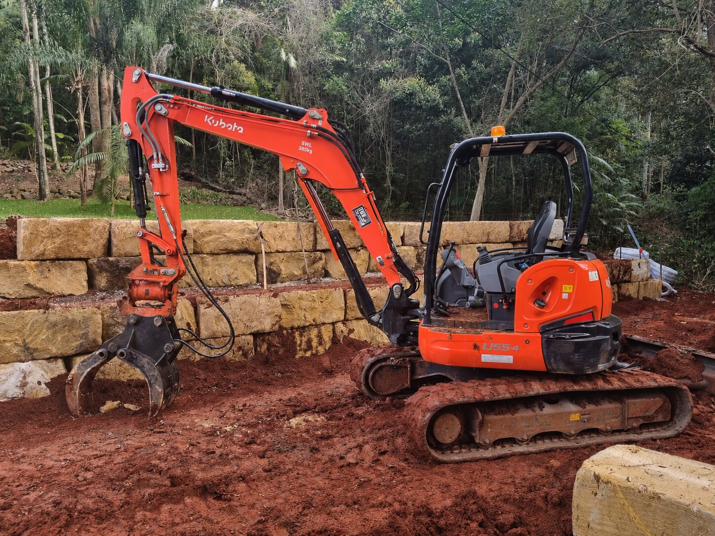 Red Kubota excavator fitted with a hydraulic grab